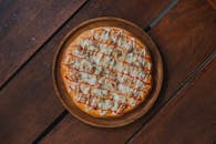 质朴的木桌上，放着令人垂涎欲滴的自制披萨，上面撒着奶酪