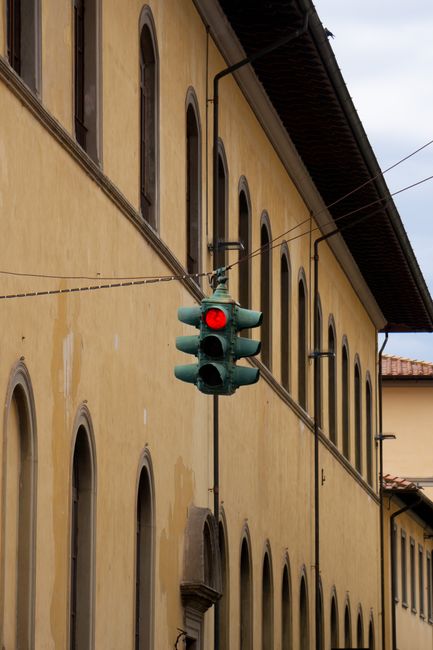Historic building facade with a red traffic light in an urban setting.