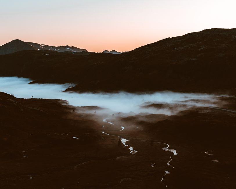 Stunning sunrise over a misty valley with mountains and a meandering stream.