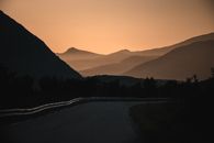 山路风景优美，日落景色壮丽，背景是山丘的轮廓