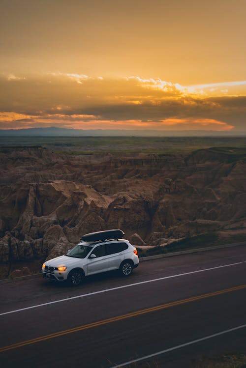 Voiture Sur Le Côté De La Route Près D'un Terrain De Montagne Au Coucher Du Soleil