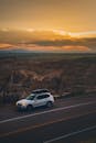 日落时分，一辆汽车沿着蜿蜒的道路行驶，沿途是令人惊叹的山地景观