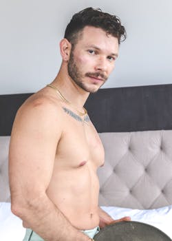 Portrait of a shirtless man indoors exuding masculinity and strength.