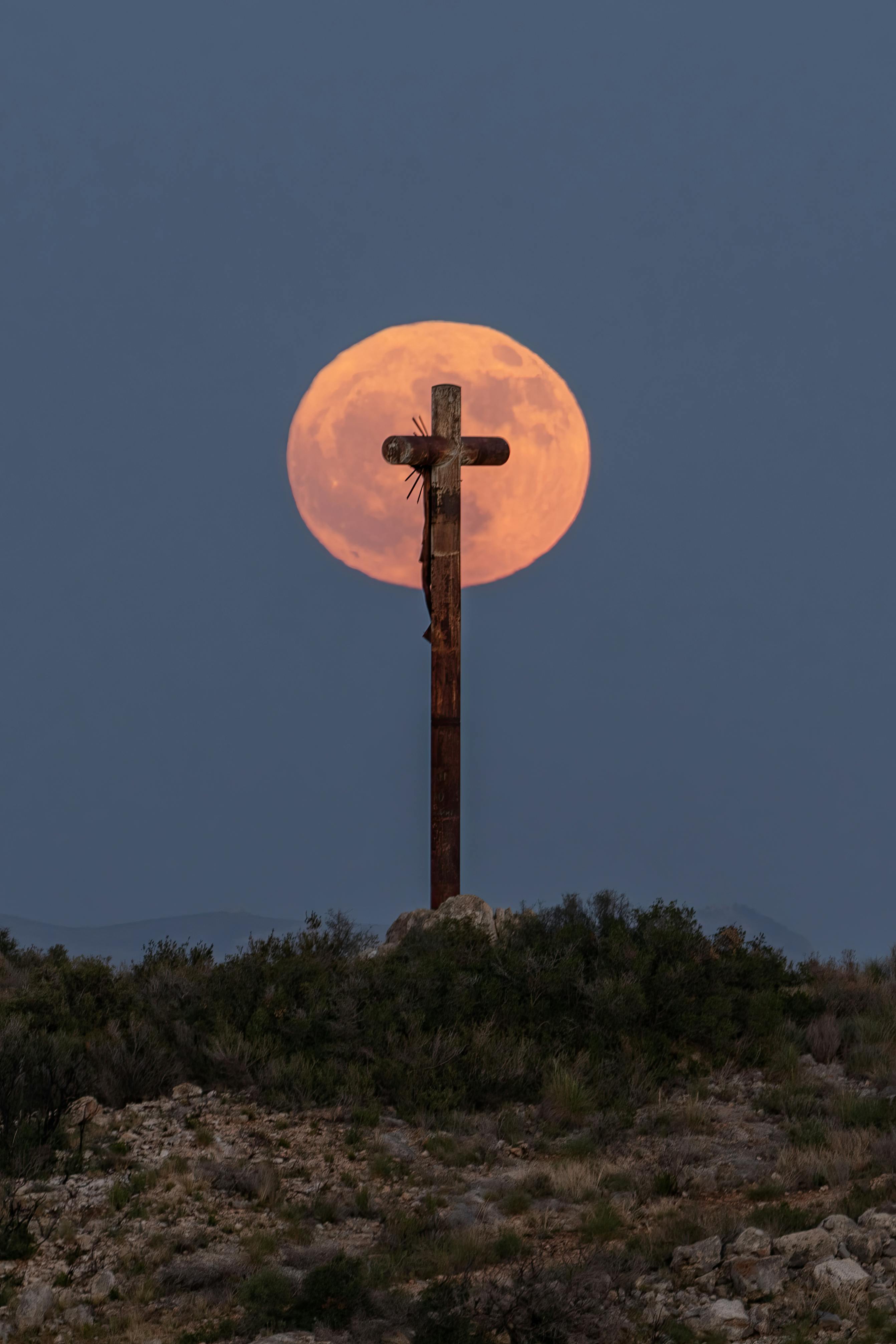 the moon behind a cross