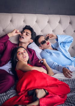 Three stylish young adults in fashionable attire lounging indoors on a sofa.