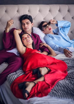 Three adults in fashionable attire lounging on a modern sofa, highlighting relaxed lifestyle and togetherness.