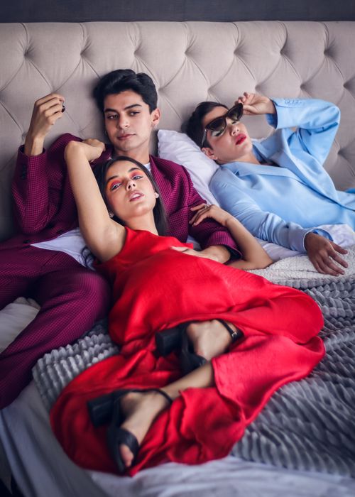 Free Three adults in fashionable attire lounging on a modern sofa, highlighting relaxed lifestyle and togetherness. Stock Photo