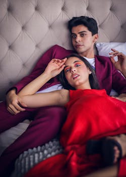 A stylish couple in vibrant attire relaxing on a tufted sofa, embodying modern romance.
