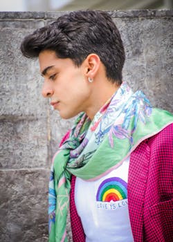 Young man in colorful attire, outdoors with a pride-themed shirt showing 'Love is Love'.