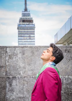 Side profile of a stylish man in a vibrant pink suit against an urban cityscape with a recognizable skyscraper.