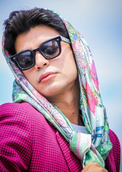 Stylish portrait of a man wearing sunglasses and a floral scarf outdoors, exuding confidence.