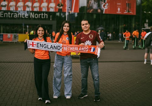 Family posing with England vs Netherlands scarf outside Dortmund stadium for UEFA Euro 2024.