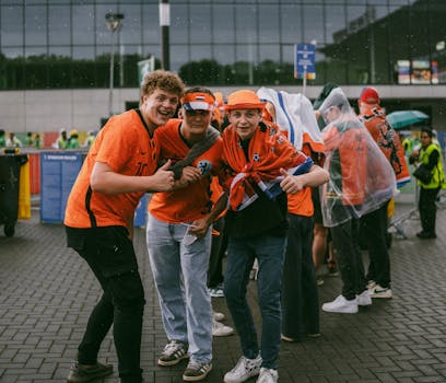 A group of Dutch soccer fans posing in vibrant orange jerseys outside a stadium.