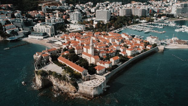 Drone view of Budva's scenic old town with red roofs and coastal beauty.