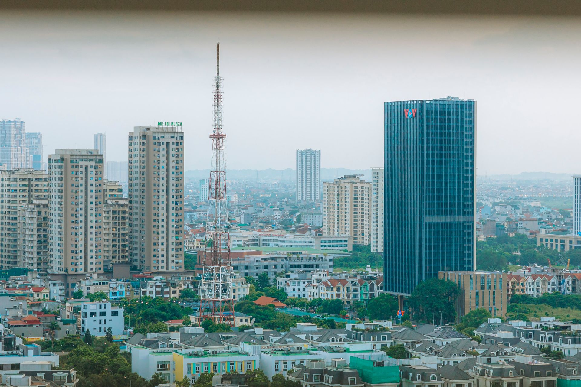 A panoramic view of a modern city skyline with high-rise buildings and communication towers.