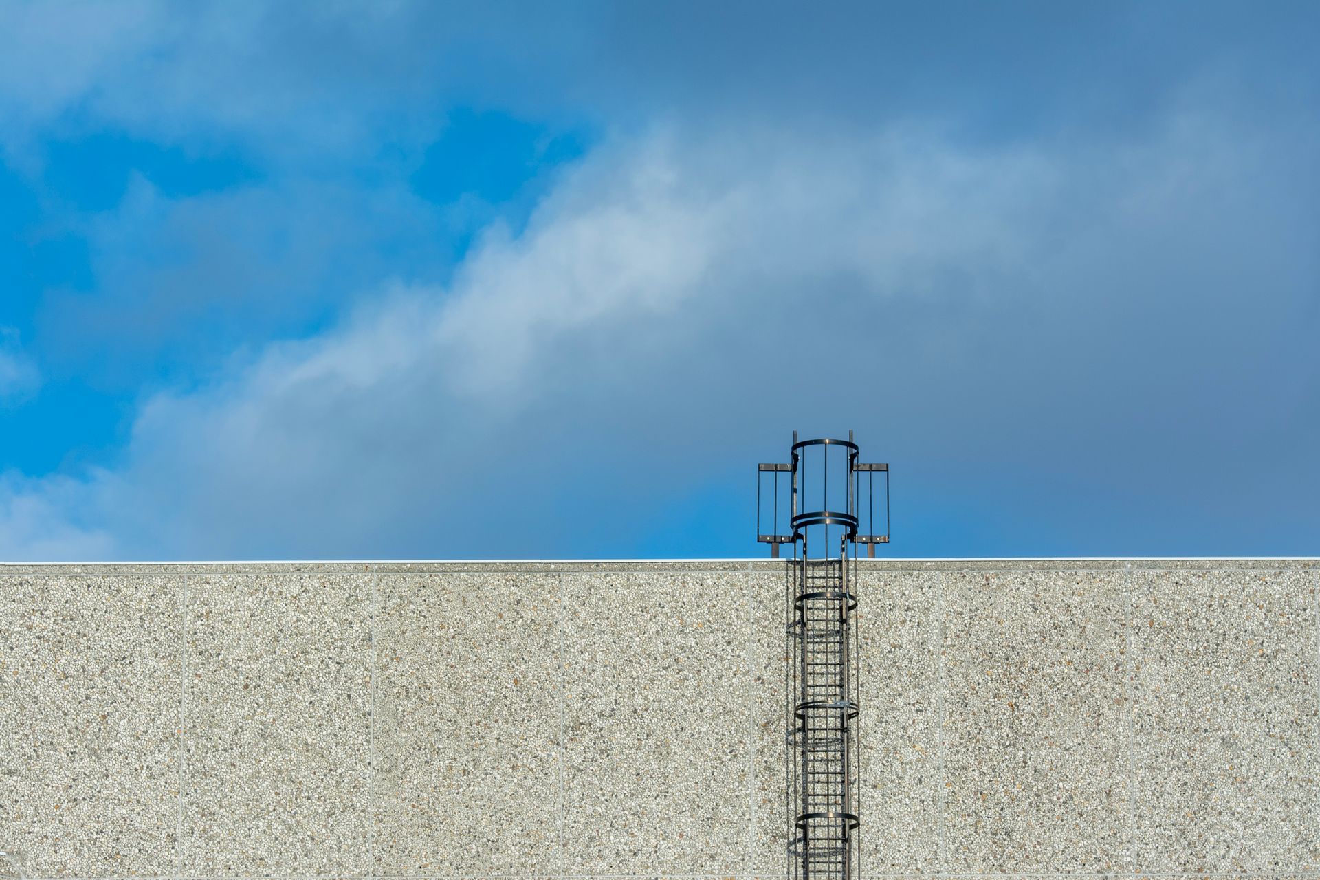 A steel antenna on a building rooftop with a clear blue sky in the background.