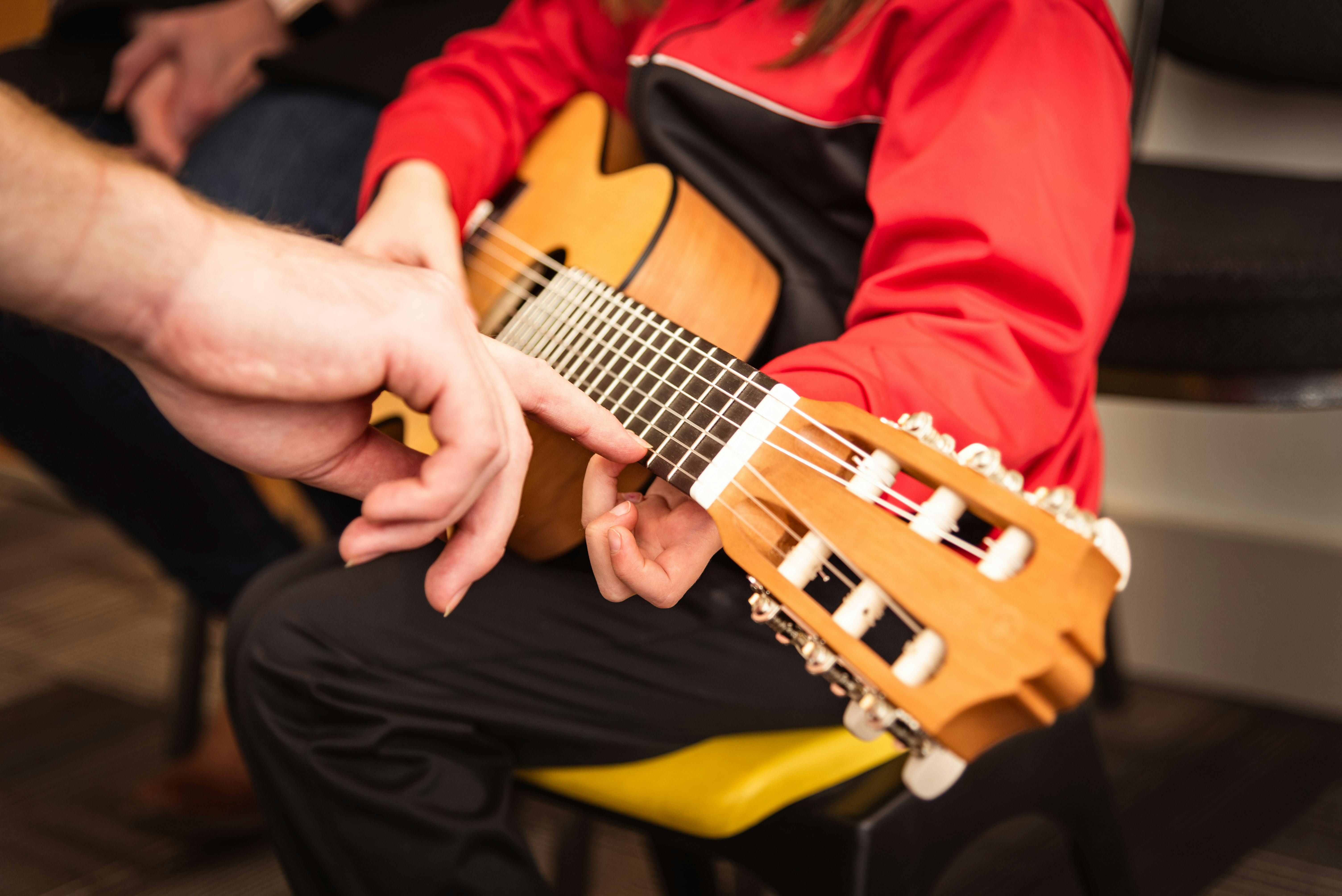 Child receiving guitar lesson with instructor's guidance in Victoria, BC. Focused on strings and technique.