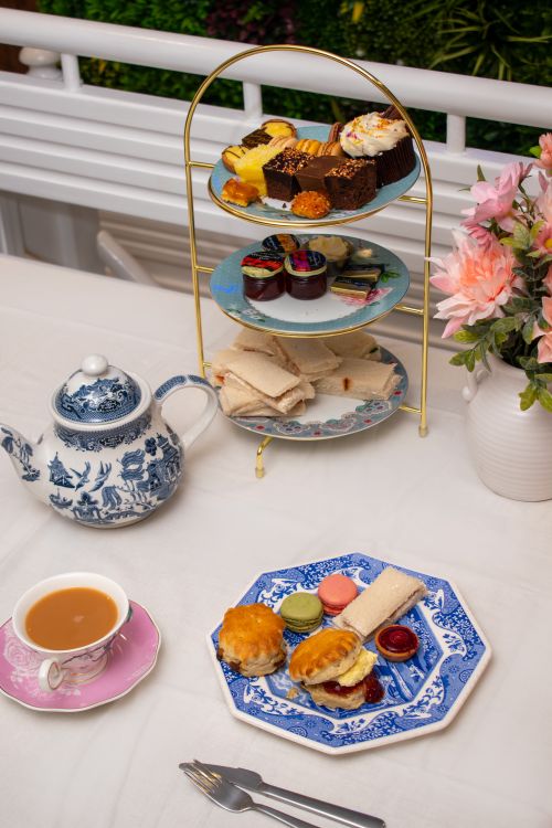Free A luxurious afternoon tea setup featuring desserts, sandwiches, and a floral arrangement. Stock Photo