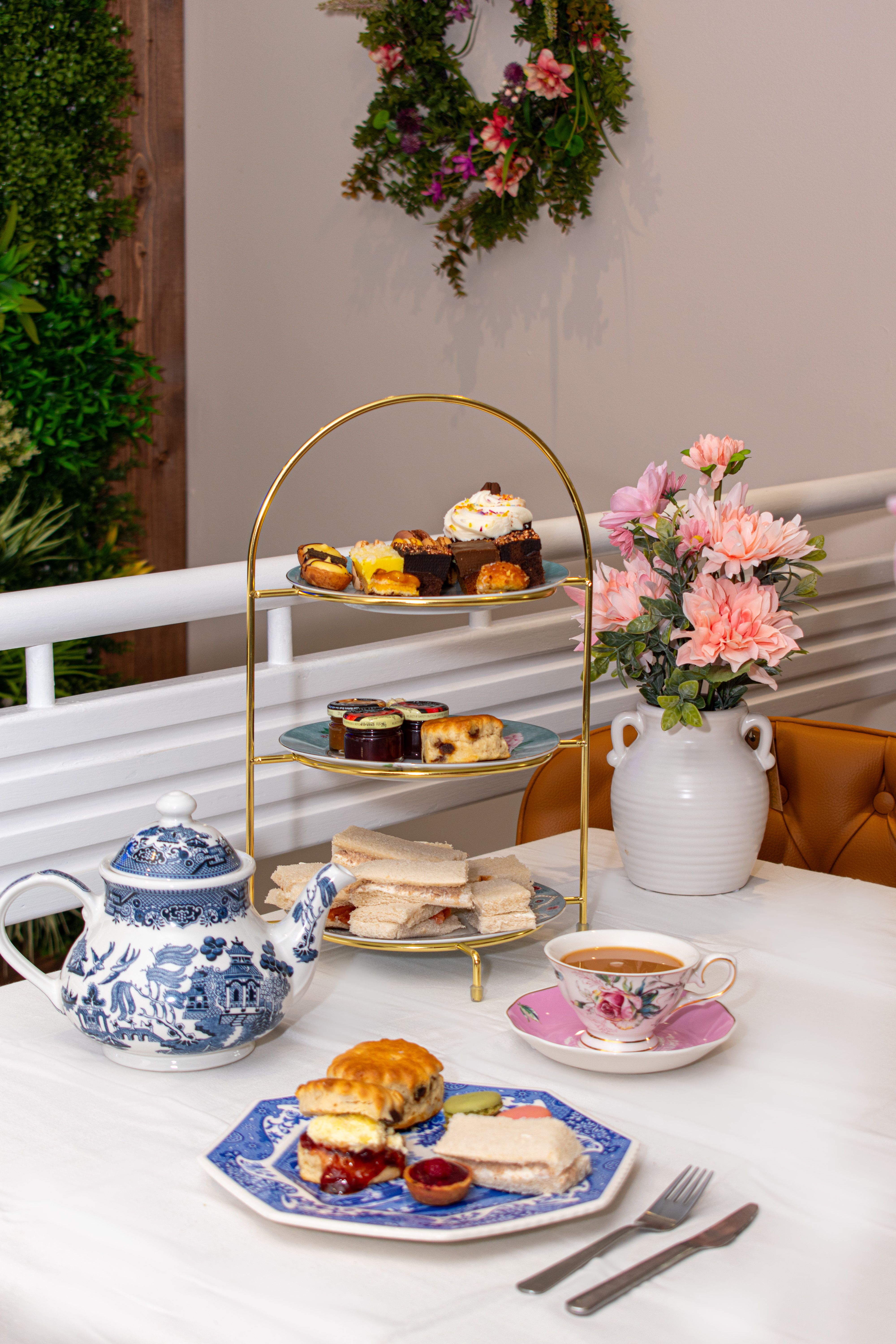Tiered afternoon tea stand with finger sandwiches, scones and pastries in a grand London hotel salon