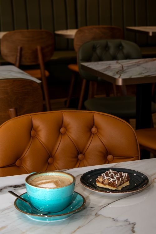 Free Elegant coffee and pastry setting on a marble table in a stylish indoor cafe with leather seating. Stock Photo