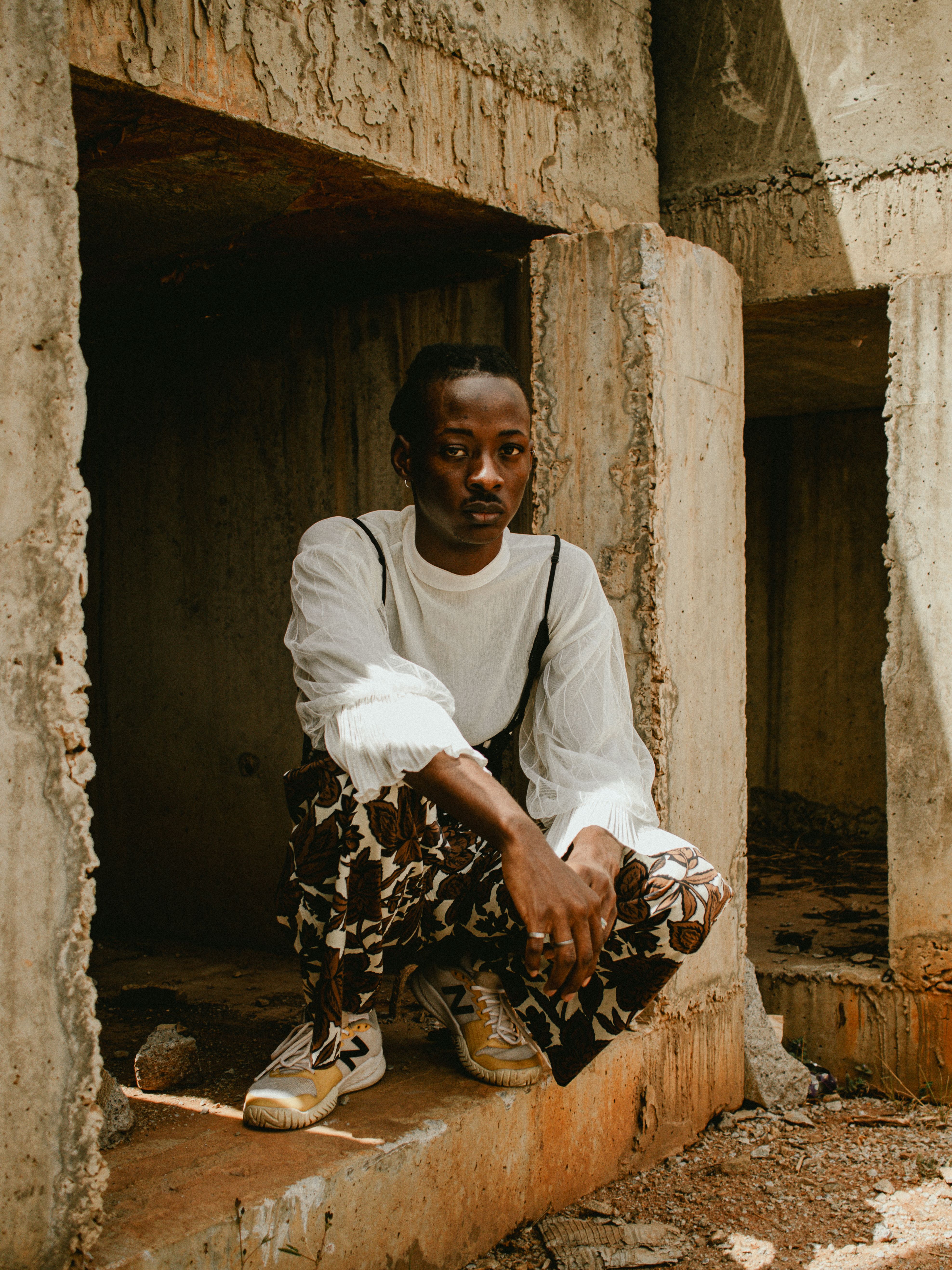 Man posing in urban setting with distinctive patterned pants and relaxed posture.