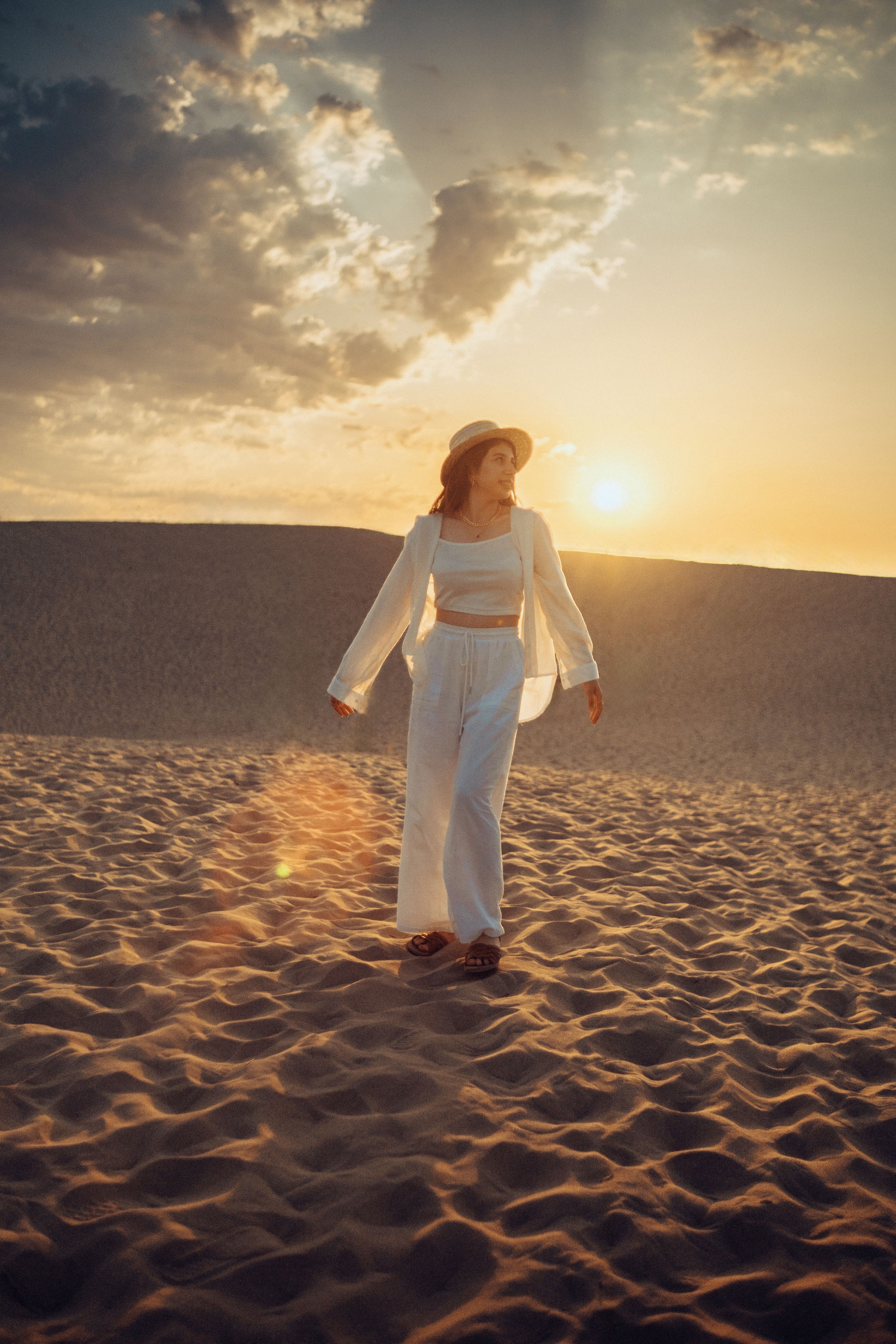 Woman in Shirt and Hat Walking on Desert at Sunset · Free Stock Photo