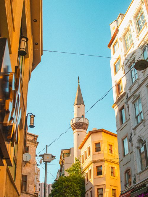 Free A vibrant street in Istanbul with traditional buildings and a beautiful mosque spire against a clear sky. Stock Photo