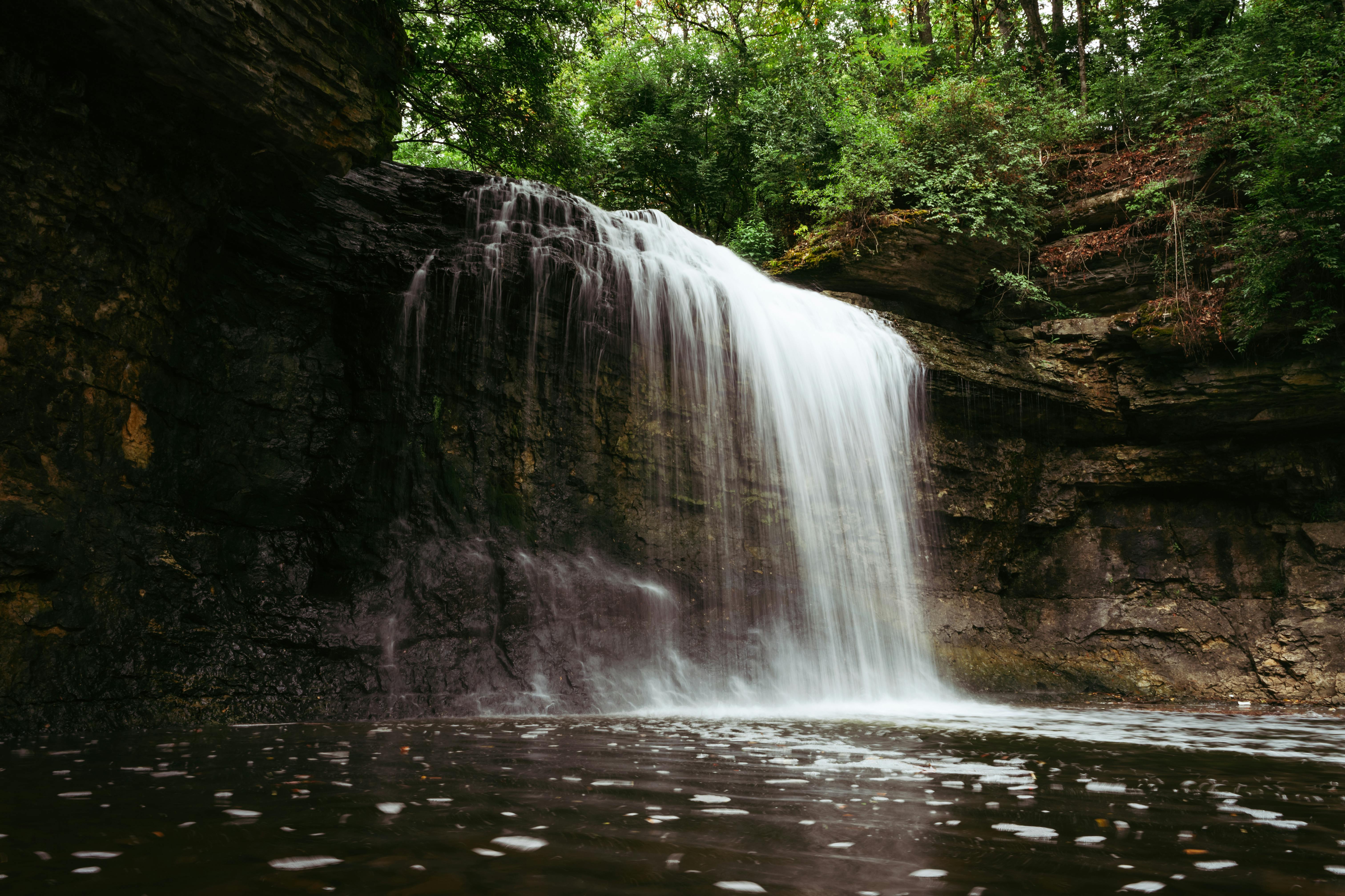 A serene waterfall cascading over rocky cliffs surrounded by lush green foliage.