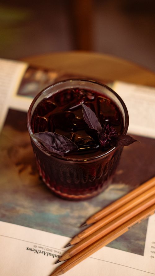 Free A glass of iced tea with basil leaves placed on an antique-style table. Stock Photo