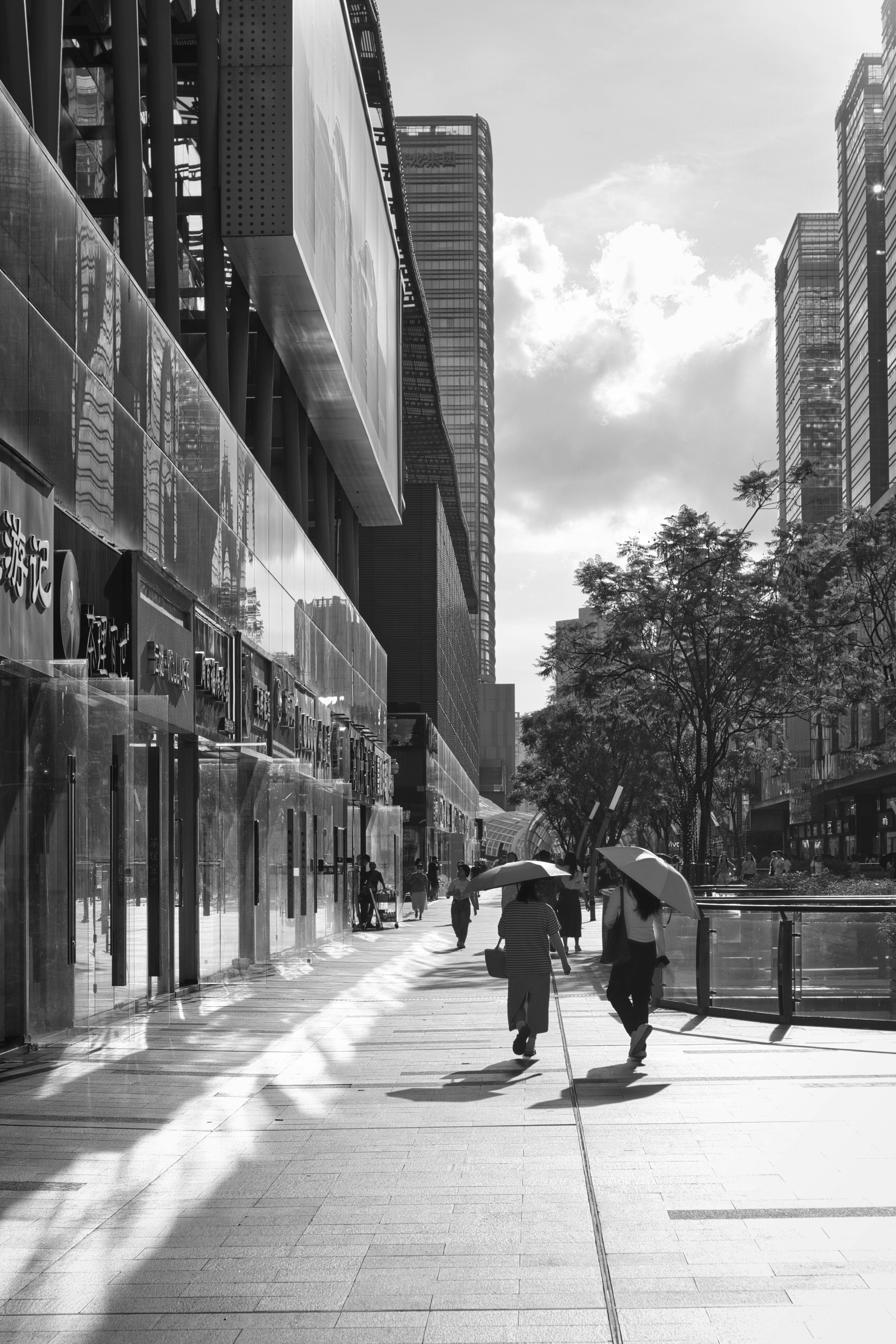 Black and white photo capturing city street with people and modern architecture.