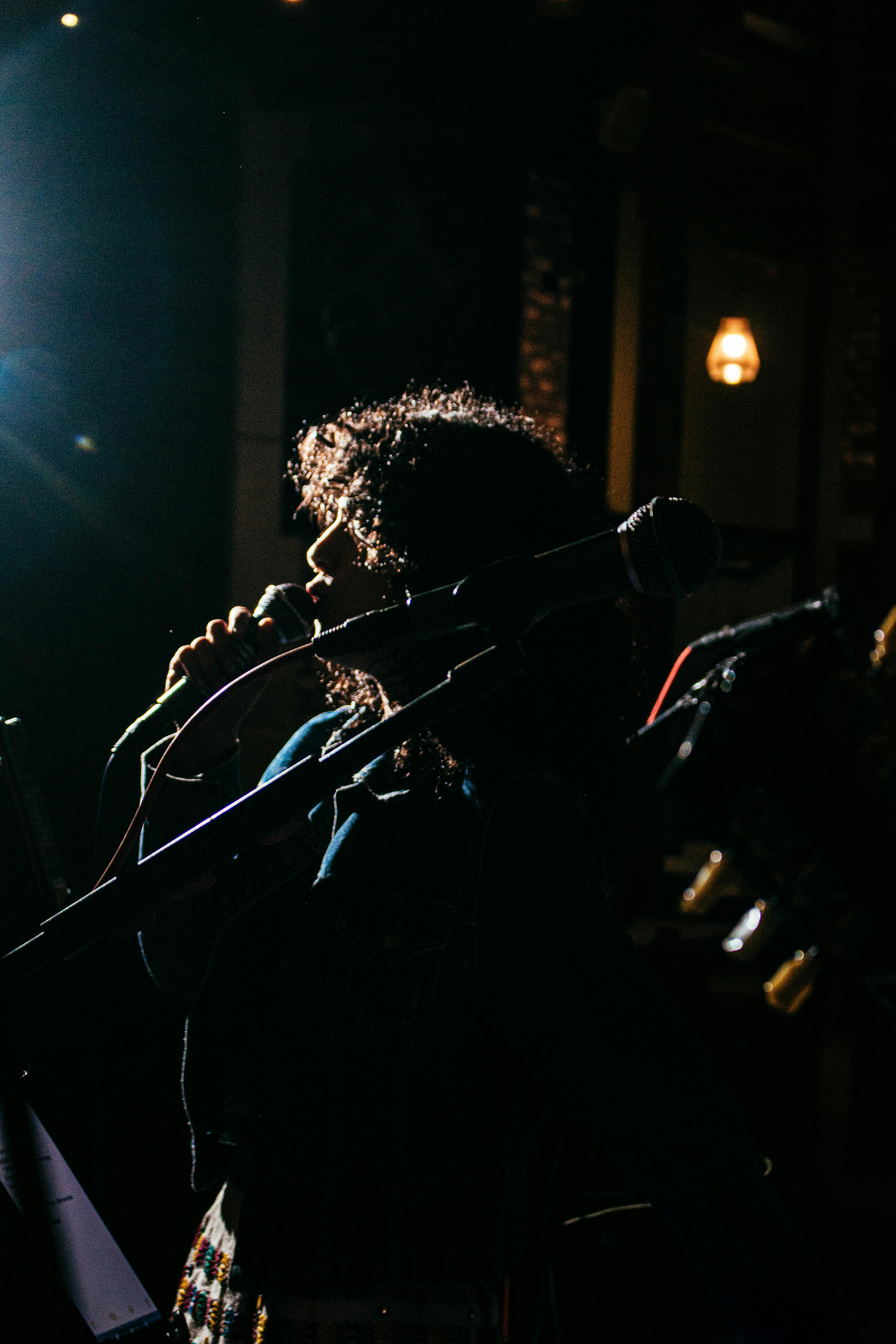 singer on dark stage singing into microphone