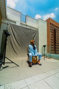 Stylish model wearing blue attire on a rooftop with city skyline backdrop.