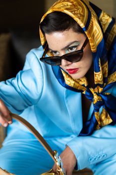 Fashionable woman in sunglasses and blue suit wearing a golden scarf, Mexico City.