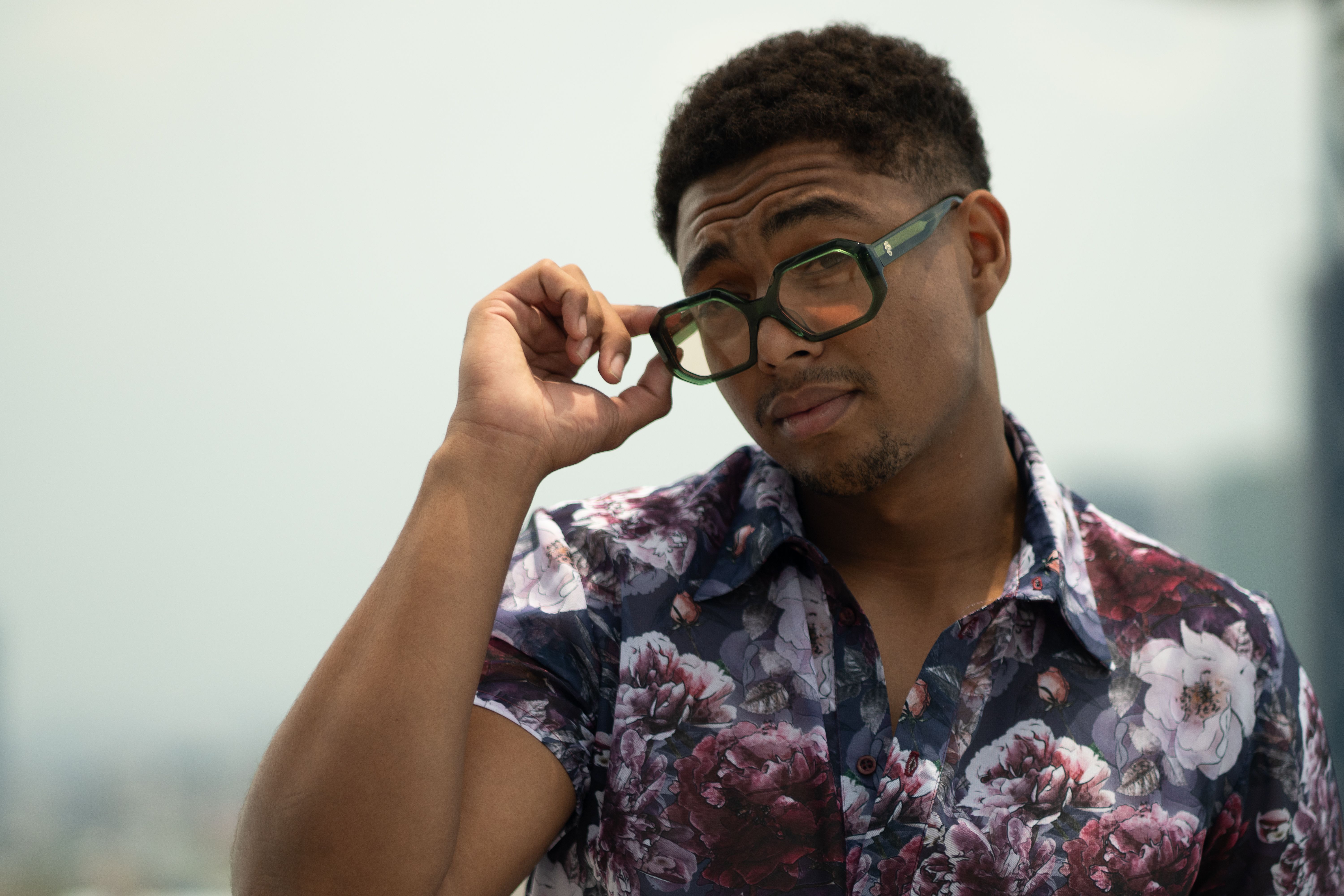 Portrait of a stylish man in a floral shirt and glasses, Mexico City skyline.