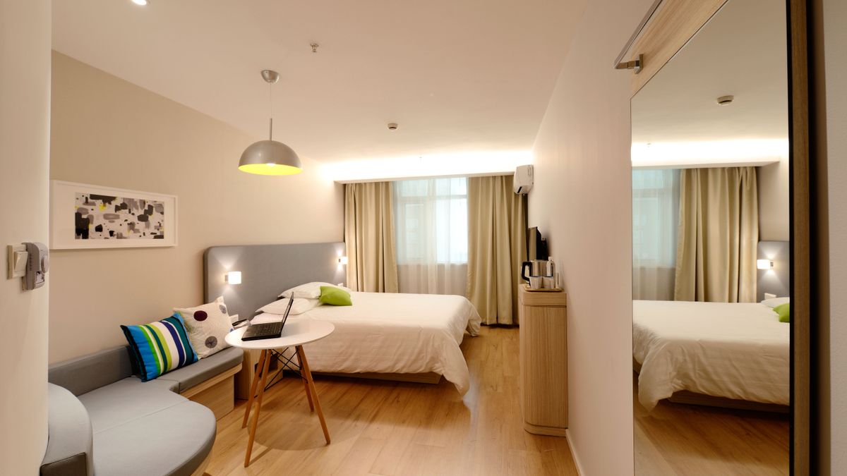A spacious modern hotel room with a large bed and balcony, the kind of stay covered by card travel protection