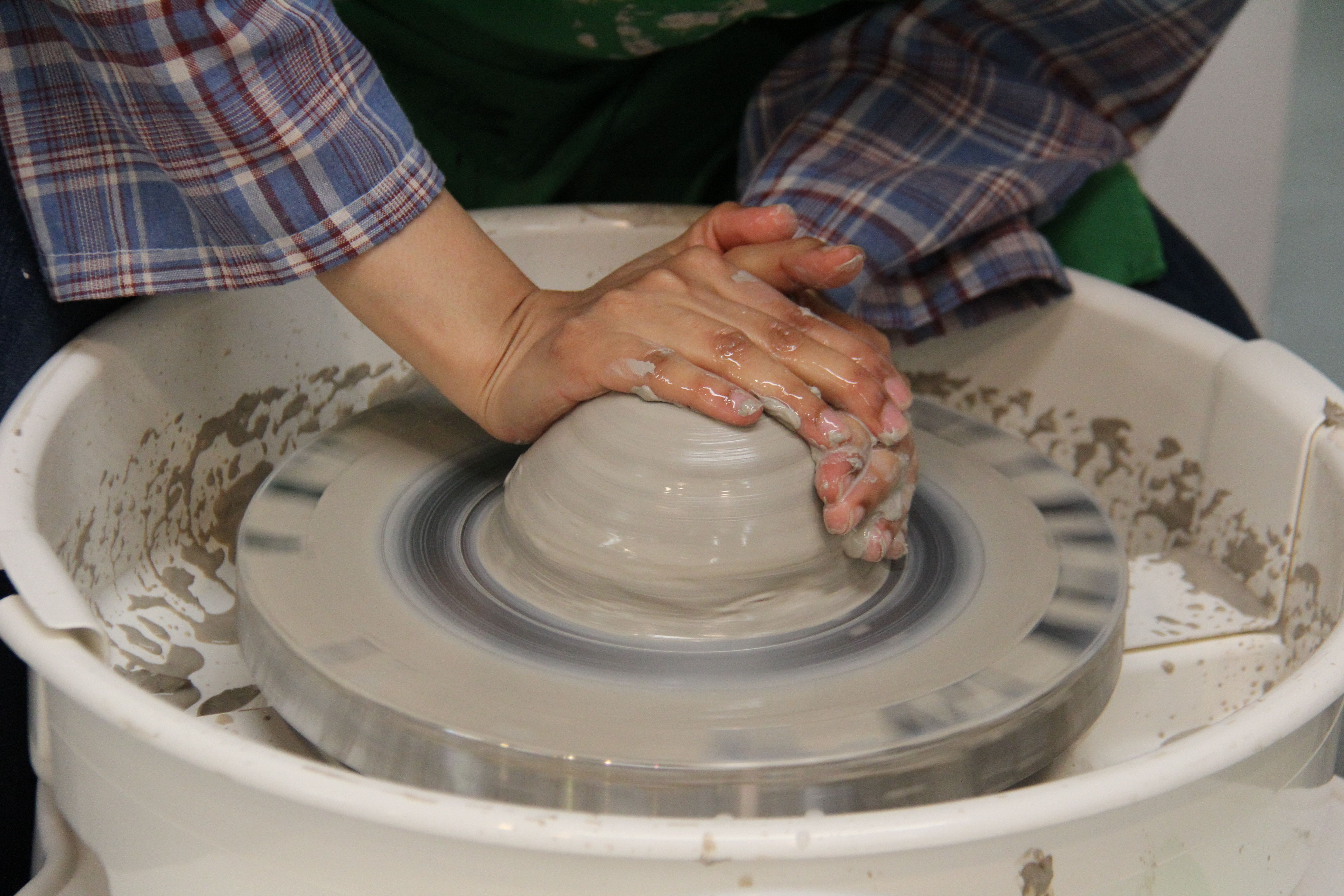 Hands expertly shaping clay on a potter's wheel, showcasing craftsmanship and creativity.