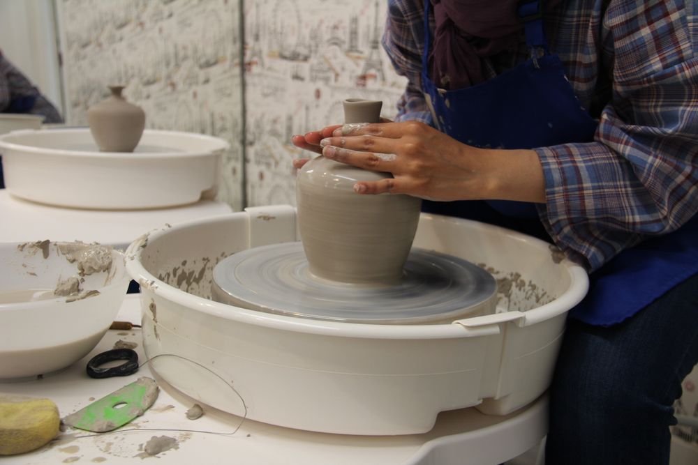 Hands shaping a clay vase on a pottery wheel