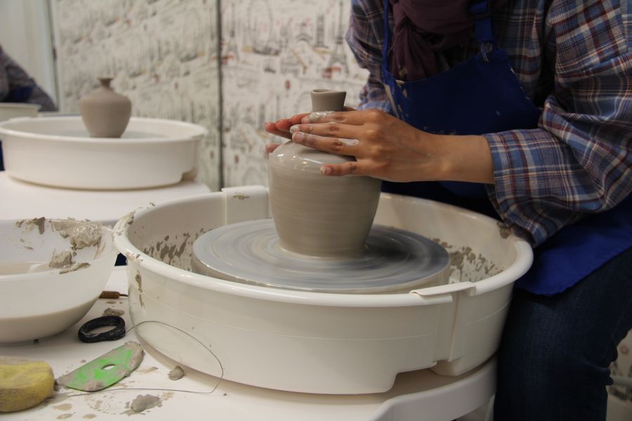 Salma-style hands shaping clay on a pottery wheel