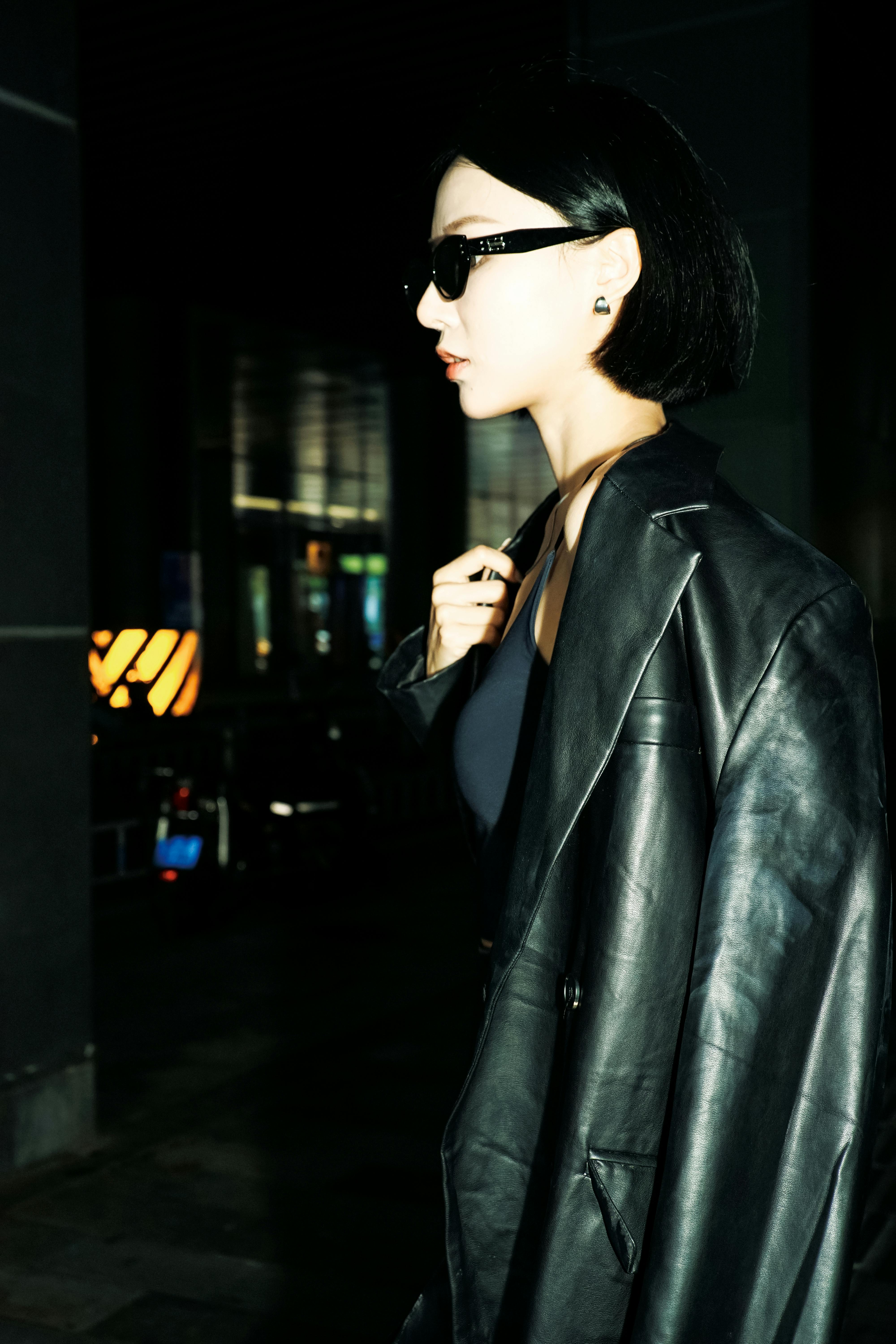 Elegant woman poses in a chic black leather coat, exuding confidence and style.