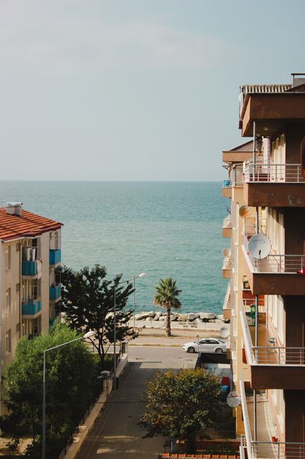 A relaxing coastal view featuring apartments and a serene sea under clear skies.