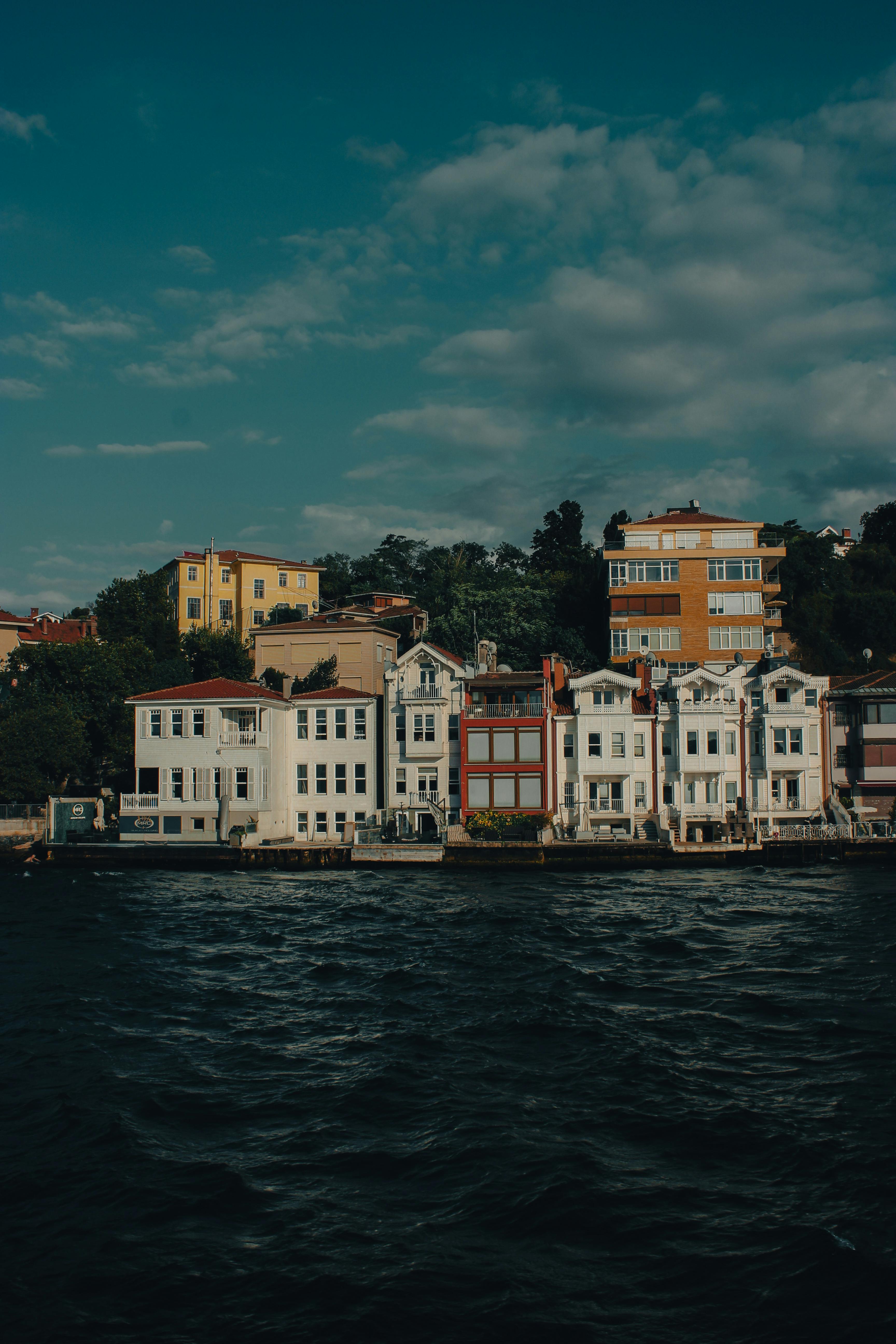 Colorful coastal homes in Türkiye line a serene body of water, offering a picturesque travel view.