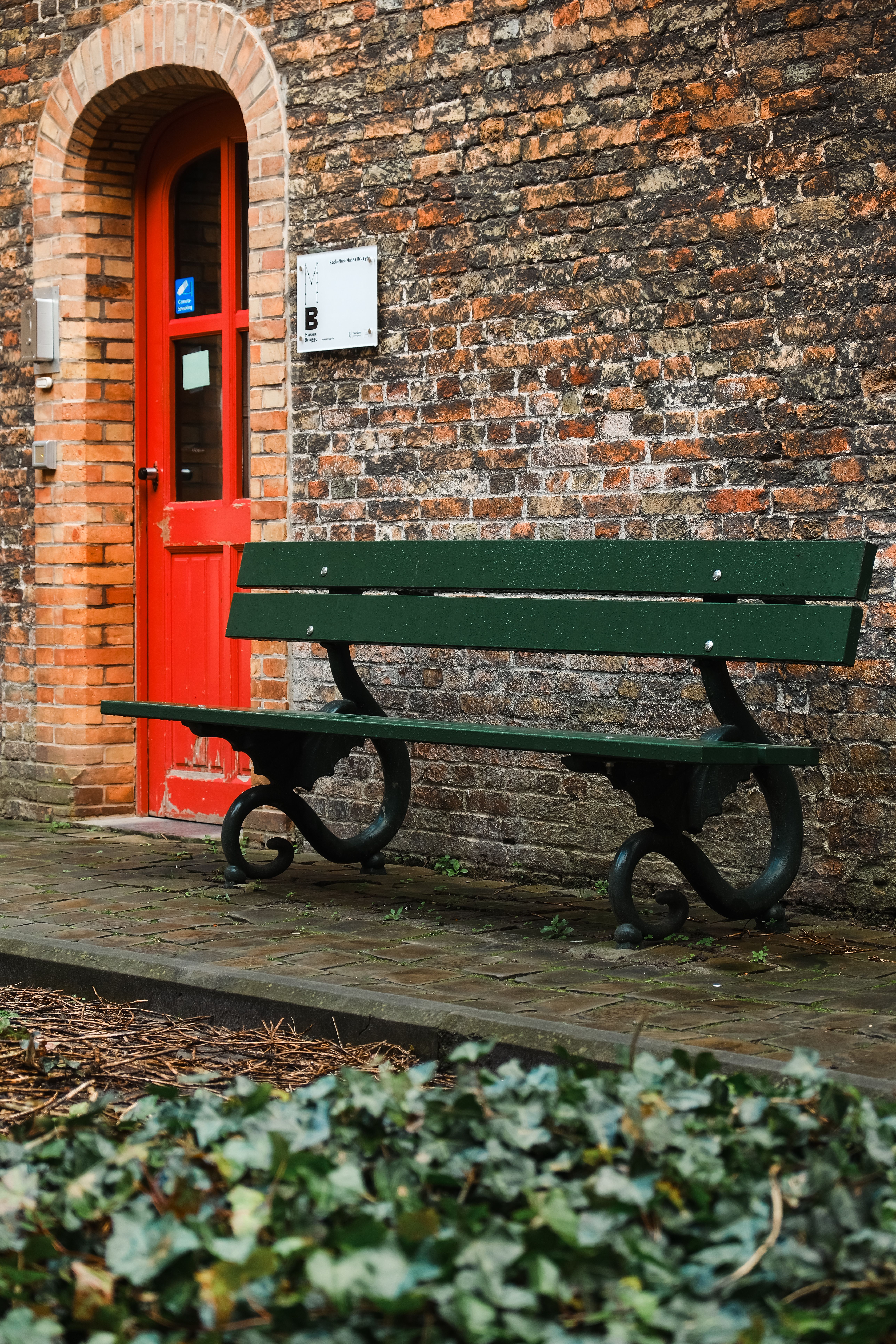 A bench sits in front of a brick building · Free Stock Photo