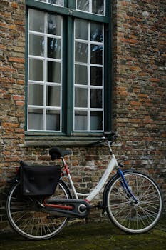 Vintage bicycle leaning against a rustic brick wall in an urban setting.