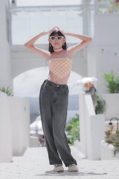 Young woman posing outdoors in trendy summer outfit with sunglasses.