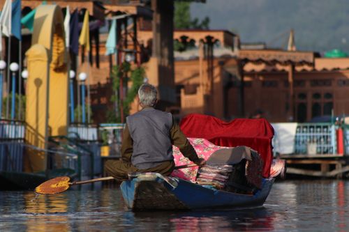 Free A traditional boat scene with a man paddling through a vibrant water market under daylight. Stock Photo