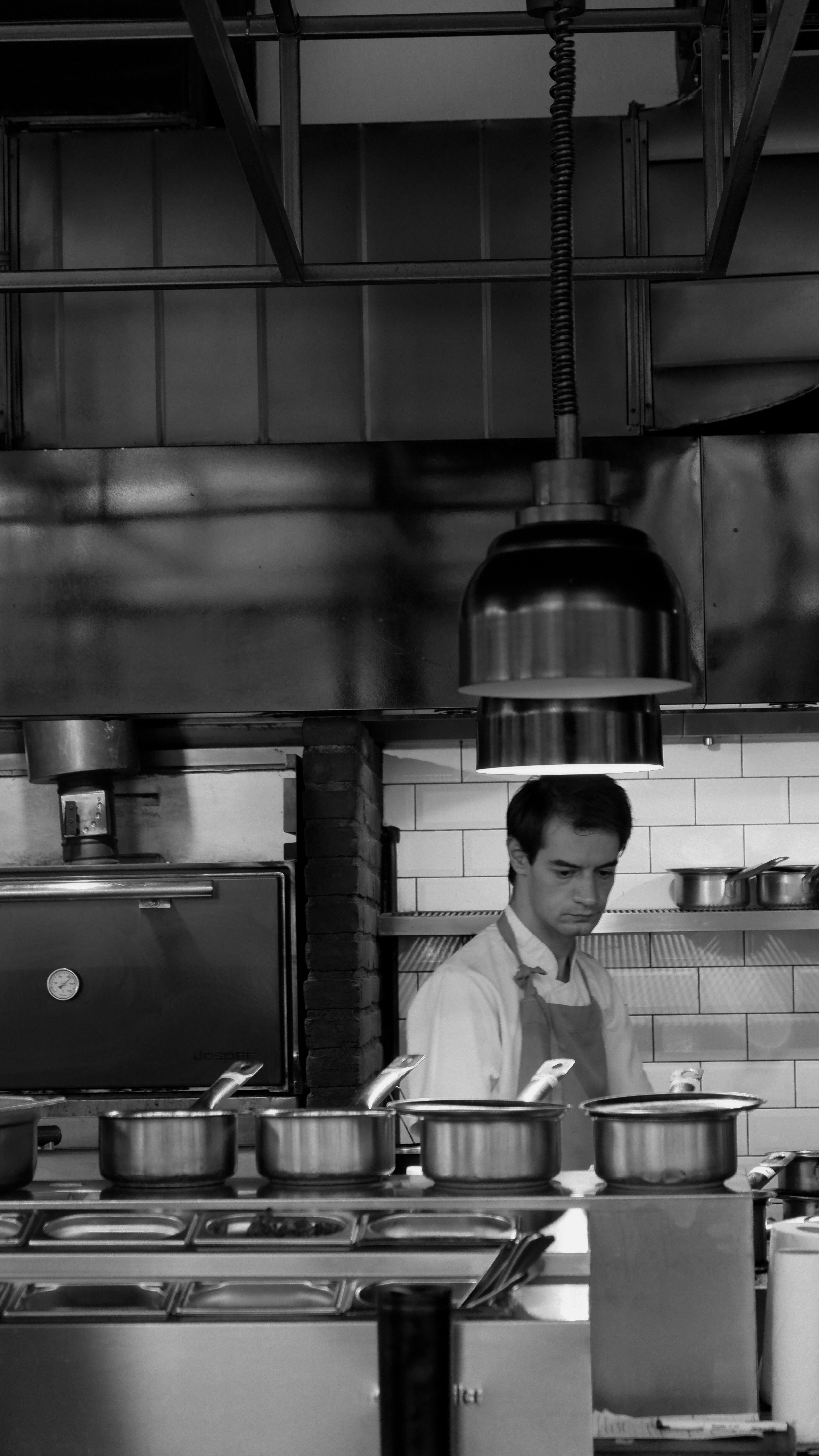 Cuisinier au travail dans une cuisine industrielle entourée de casseroles et de matériel de cuisson