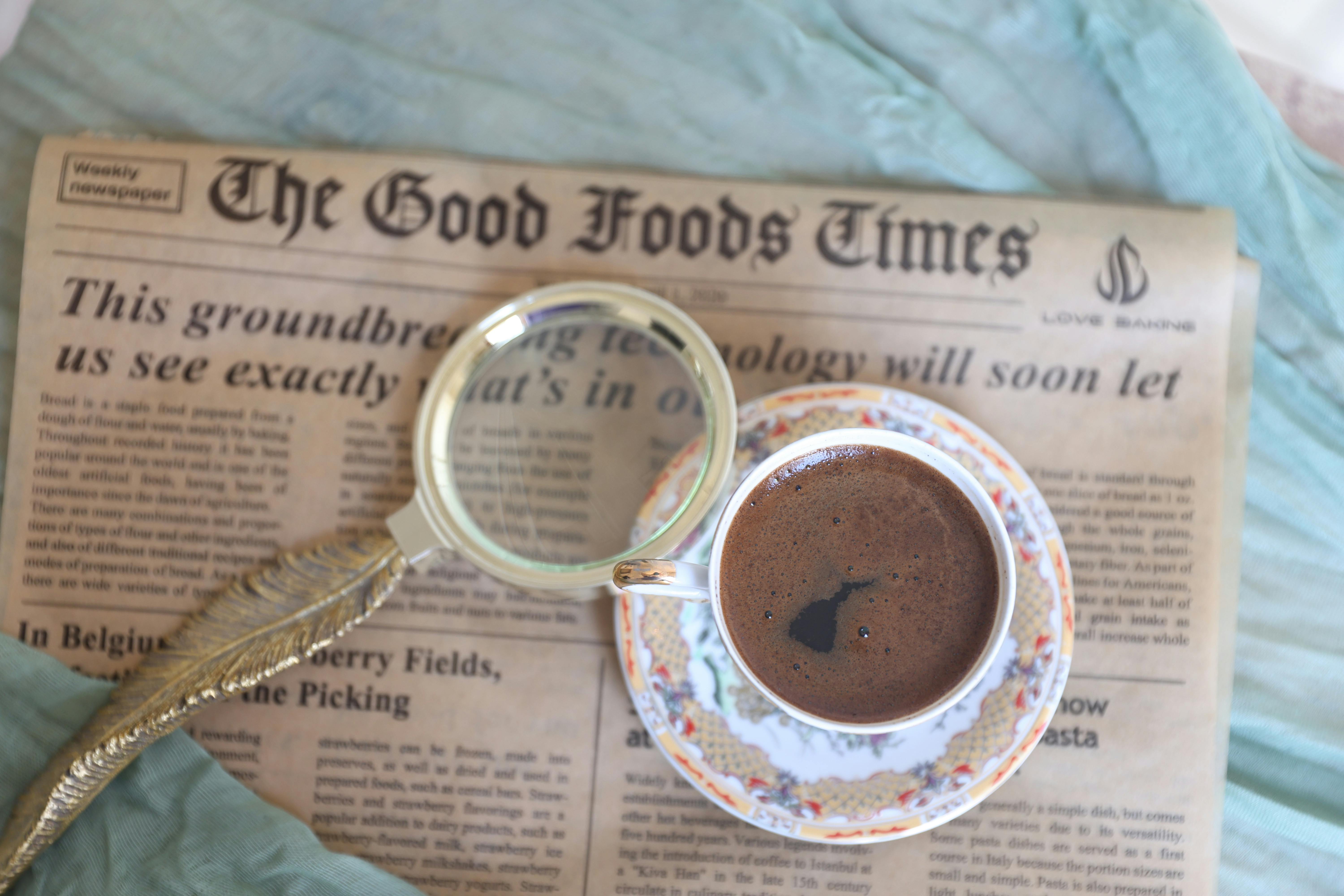 cup of coffee with saucer and magnifying glass on newspaper