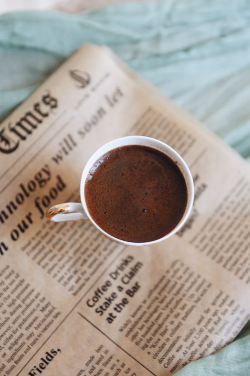 Free A steaming cup of coffee placed on a newspaper, perfect for a calm morning read. Stock Photo