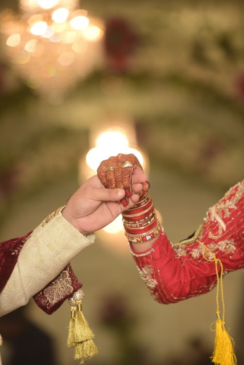 Free Close-up of a couple holding hands in traditional Indian wedding attire, symbolizing love and unity. Stock Photo