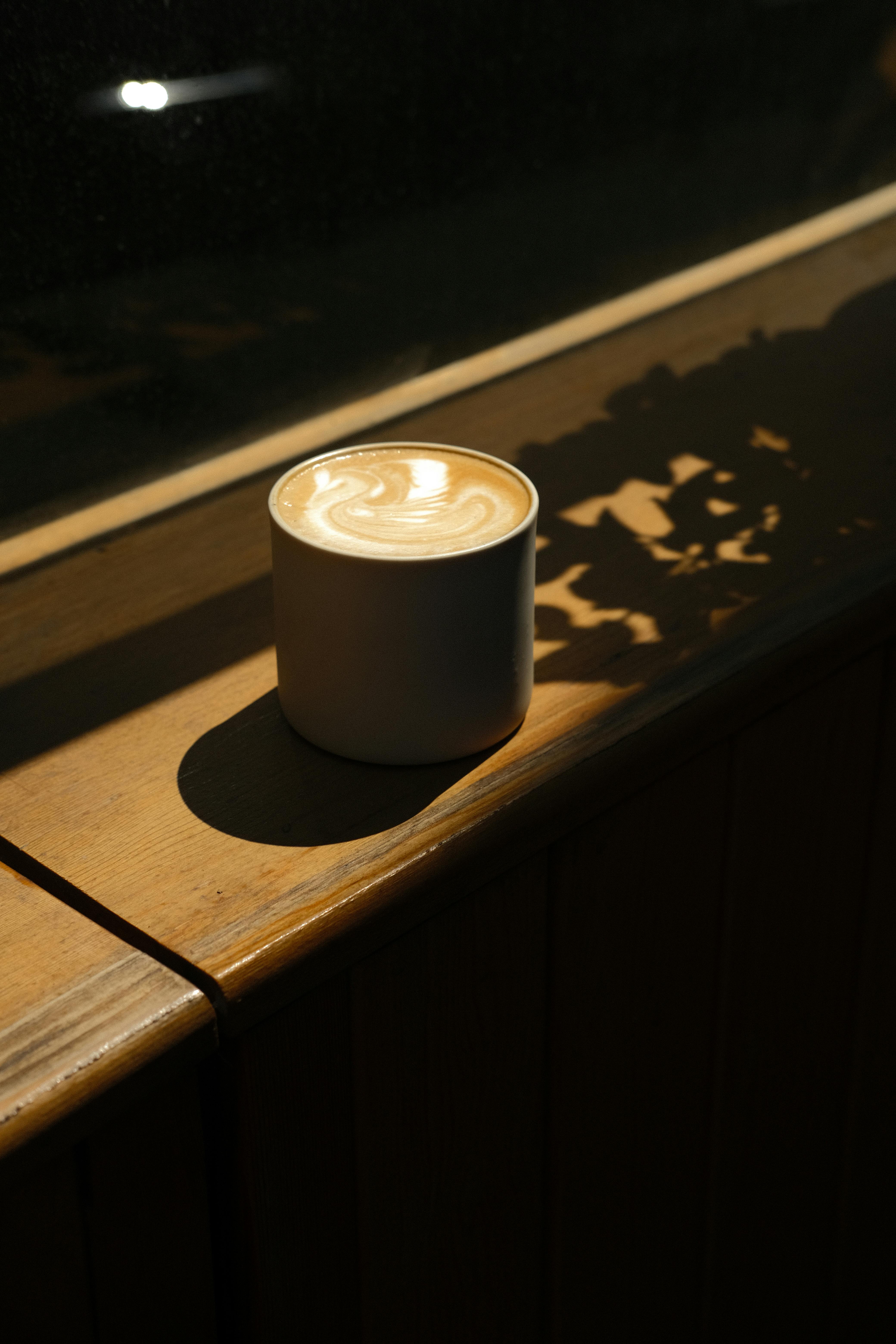 cup of coffee with latte art on wooden window sill